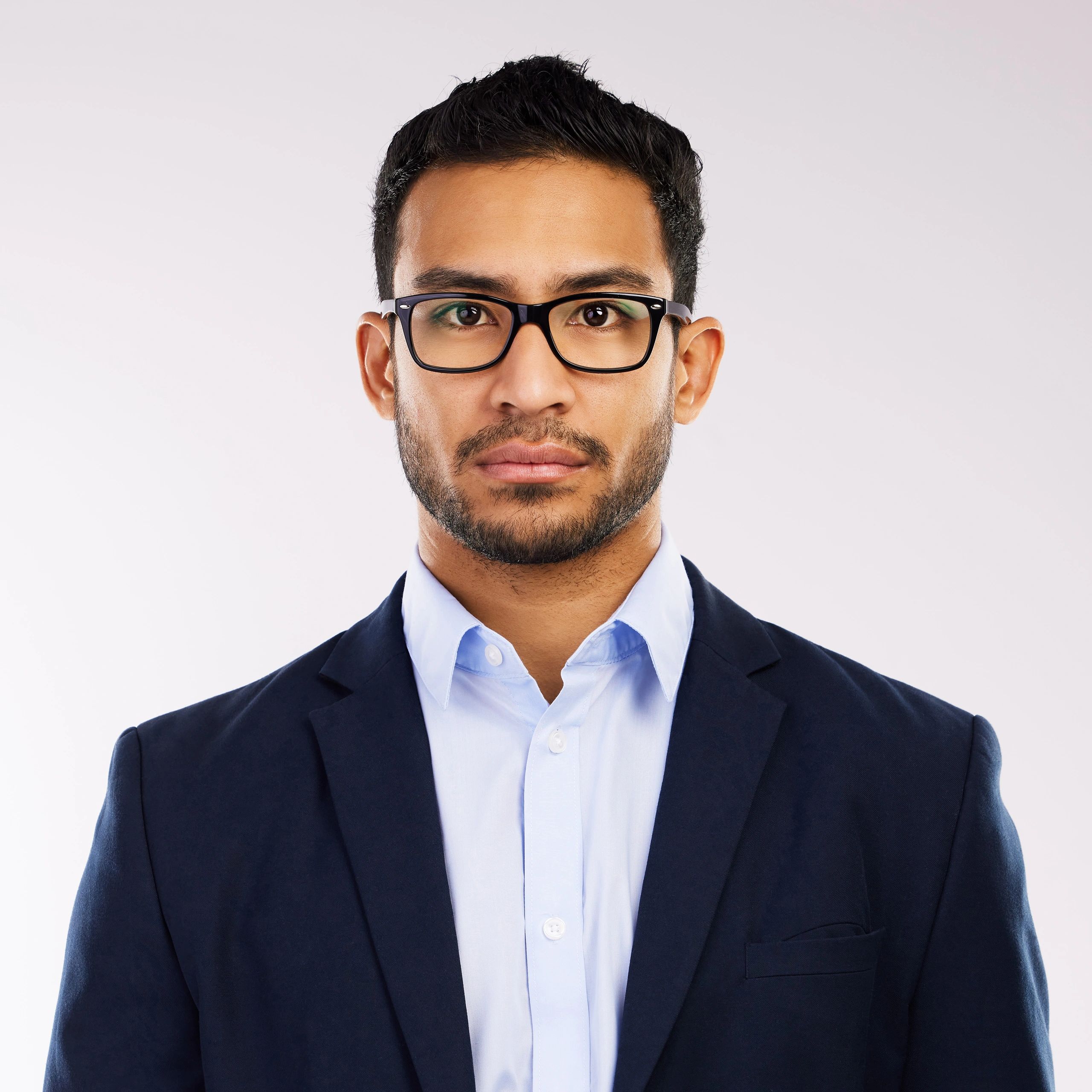 Studio headshot of a young professional man against a grey background